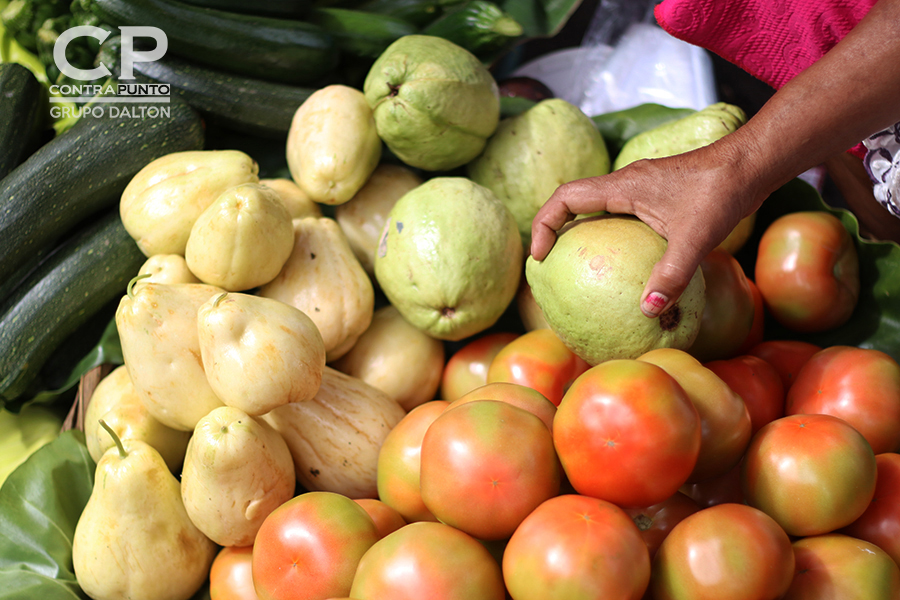 Manos que trabajan entre frutas y verduras.