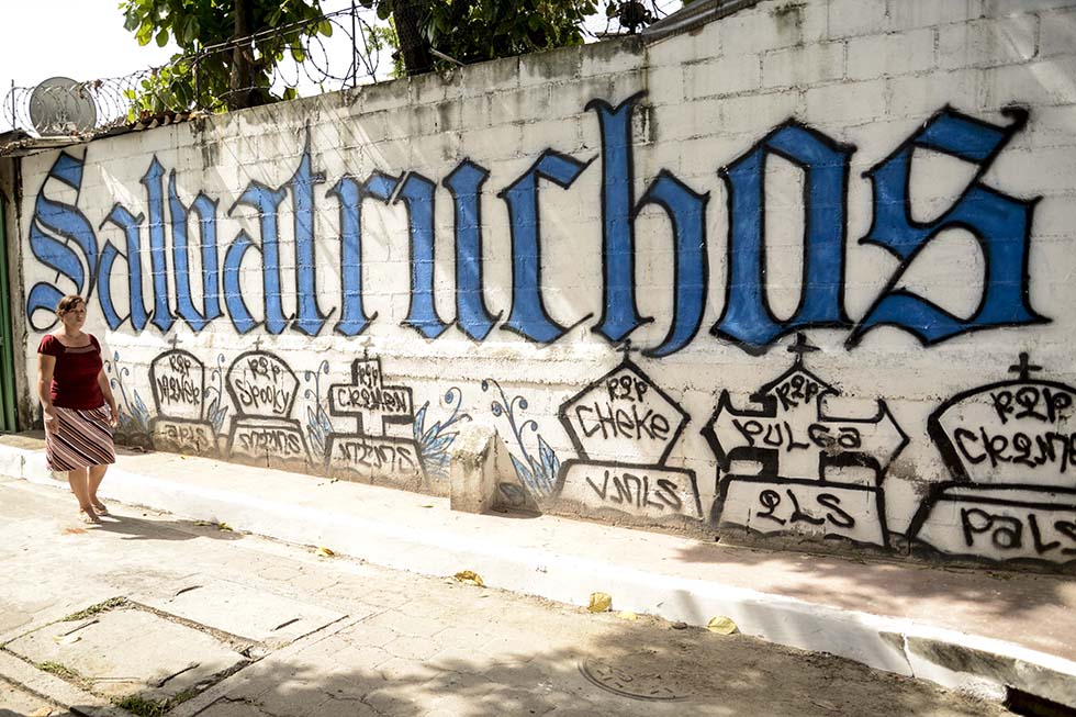 Una mujer camina frente a un grafiti de la Mara Salvatrucha en la comunidad 22 de abril, en Soyapango, lugar donde el gobierno lanzó de manera oficial el 21 de junio el plan