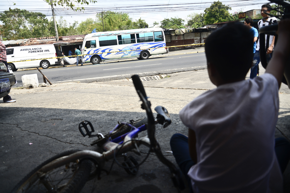 Un niño ve el traslado del cuerpo de un motorista de la ruta 6A que fue asesinado en las afueras del municipio de Mejicanos. Foto: Jessica Orellana